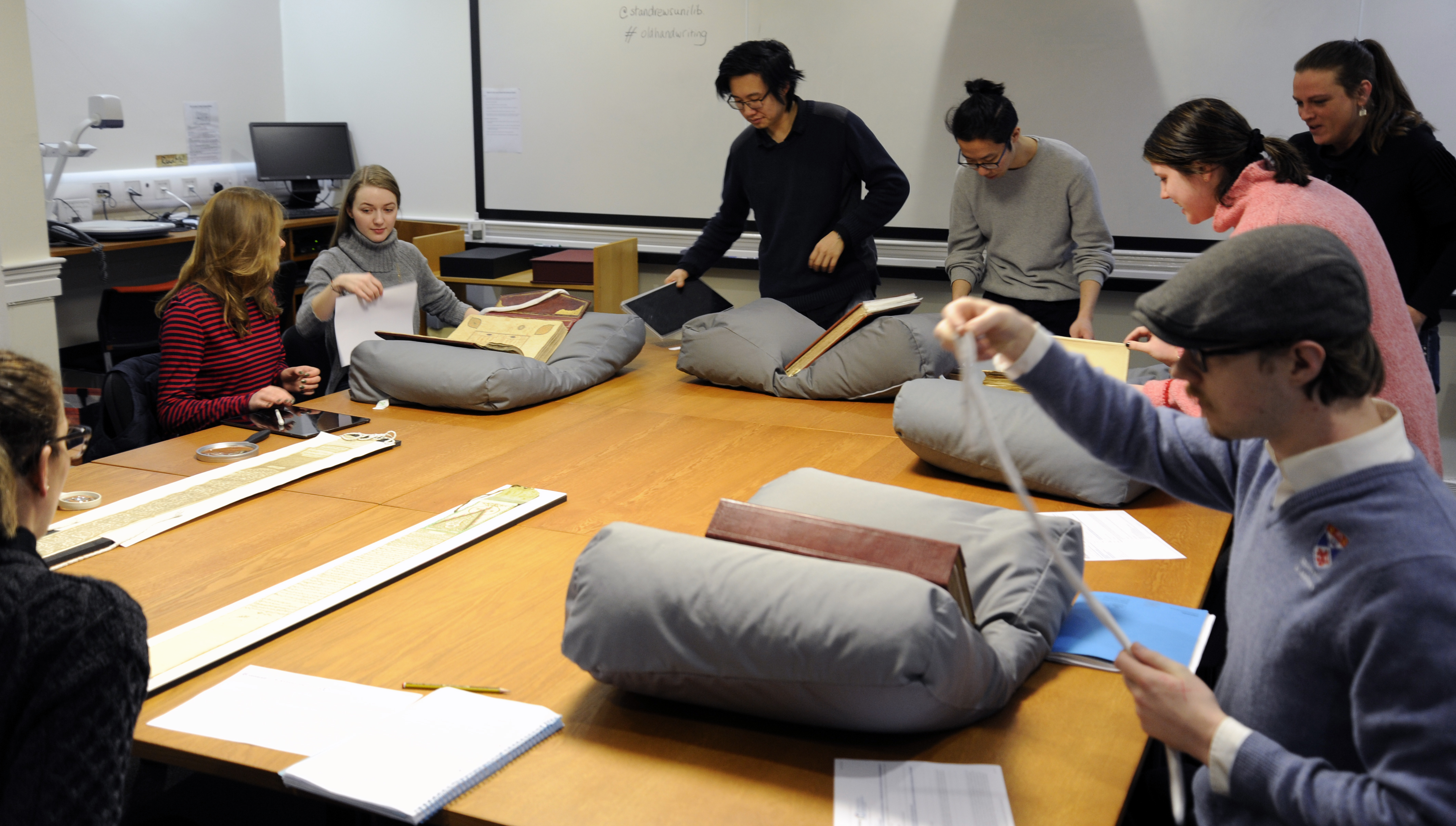 People looking at archival material laid out on a table